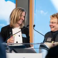 Lynn Blue smiling on stage with a friend at the Lynn M. Blue Connection Naming Ceremony
